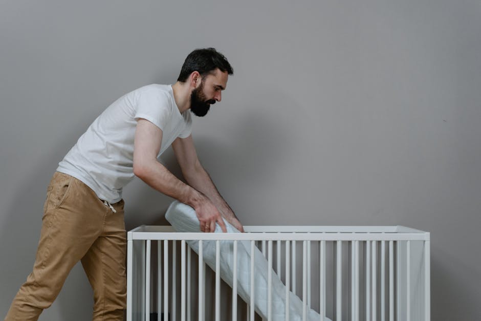 The image shows a neatly arranged bedroom with a cream-colored upholstered bed frame and a white mattress that appears to be brand new or recently replaced. The bed is positioned against a beige wall,
